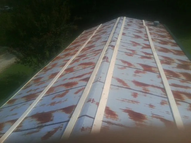 Rusted metal roof panels with new wood purlins before replacement — Storm Damage Roof Repair in New Boston by Roofing Brothers