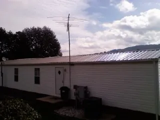New metal roof on a single wide mobile home with a TV antenna in New Boston